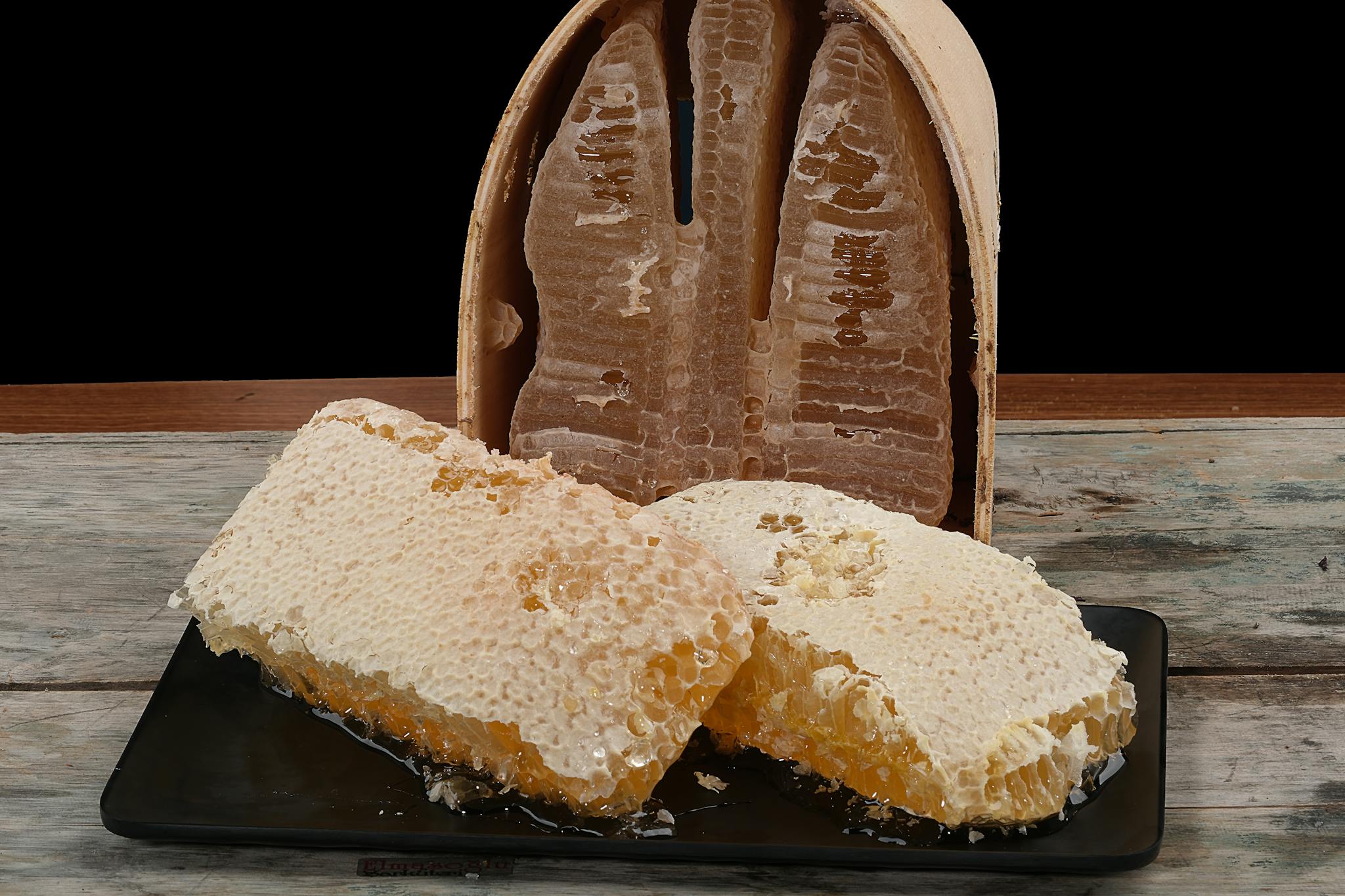 Detailed shot of fresh honeycomb on a plate against a black background, showcasing natural texture and sweetness.