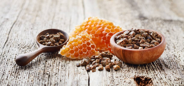 Propolis and honeycombs in wooden spoon on wooden background